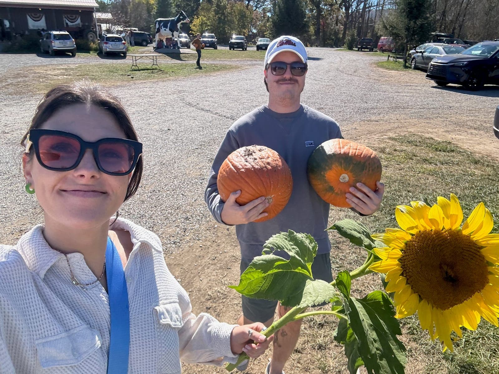 Slade holding two pumpkins next to Haley at a pumpkin patch